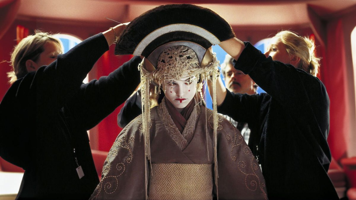 Hinter den Kulissen von Episode I: Am Set von Palpatines Apartement wird Natalie Portman das aufwendige Königinnenkostüm angelegt.